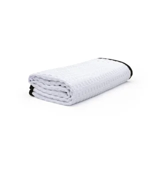 White folded textured blanket with black trim on a white background