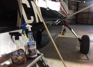 Small aircraft on hangar floor with exposed wheel and a bottle on a nearby stand
