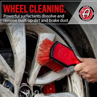 Hand scrubbing a dirty car wheel with a red brush; Wheel Cleaning ad.