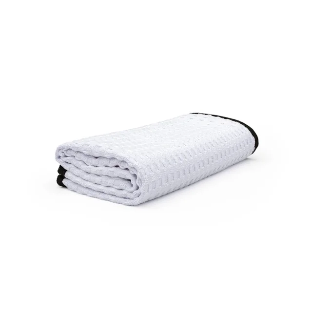 White folded textured blanket with black trim on a white background