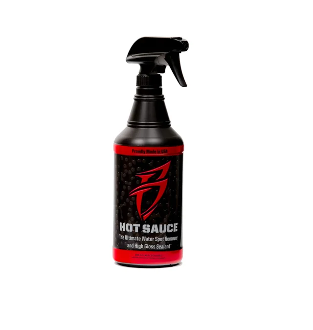 Black hot sauce spray bottle with red label on white background