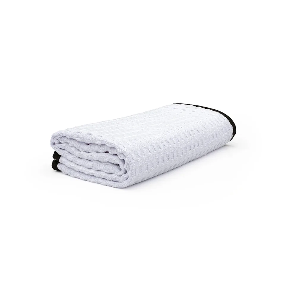 White folded textured blanket with black trim on a white background