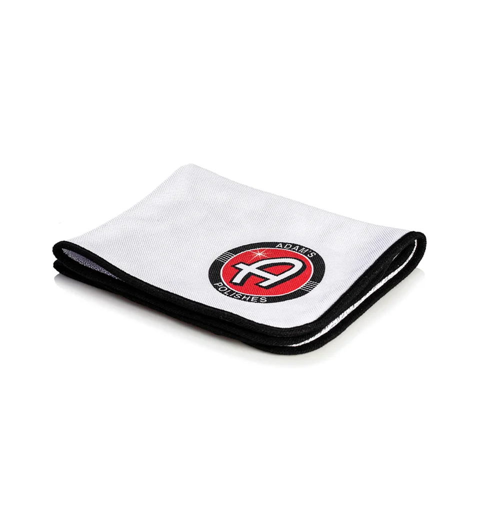 Folded white cloth with black trim and a red circular logo in the center