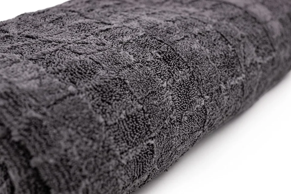 Dark gray textured towel rolled on a white background