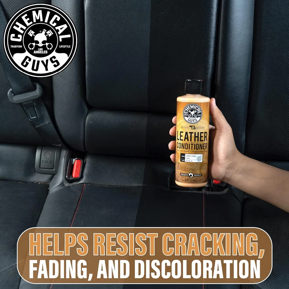 Hand holding Chemical Guys leather cleaner in a black car back seat.