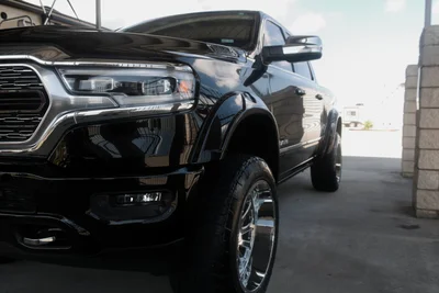 Black pickup truck parked under a covered driveway, front side view